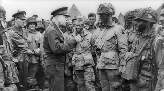 General Dwight D. Eisenhower, Supreme Commander of the Allied Expeditionary Forces in Europe, speaks with First Lieutenant Wallace C. Strobel and men of Company E, 2nd Battalion, 502nd Parachute Infantry Regiment on June 5, 1944. Strobel’s battalion was the first to drop into Normandy. Strobel survived both the Normandy invasion and the war. (US Army)